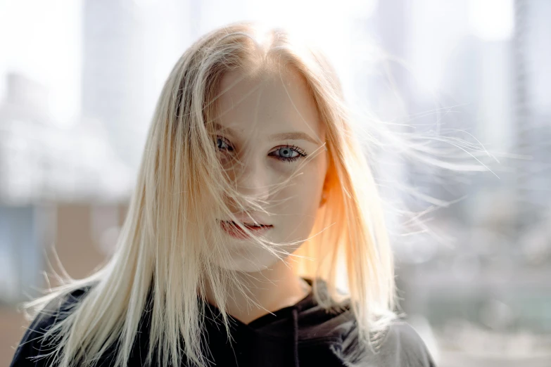 a person with blond hair standing in front of a city