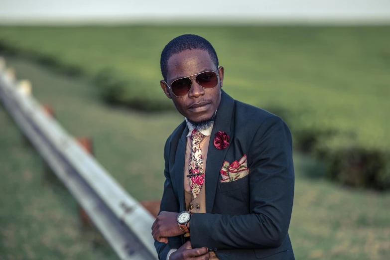 man in sunglasses and colorful shirt poses with hand on hip