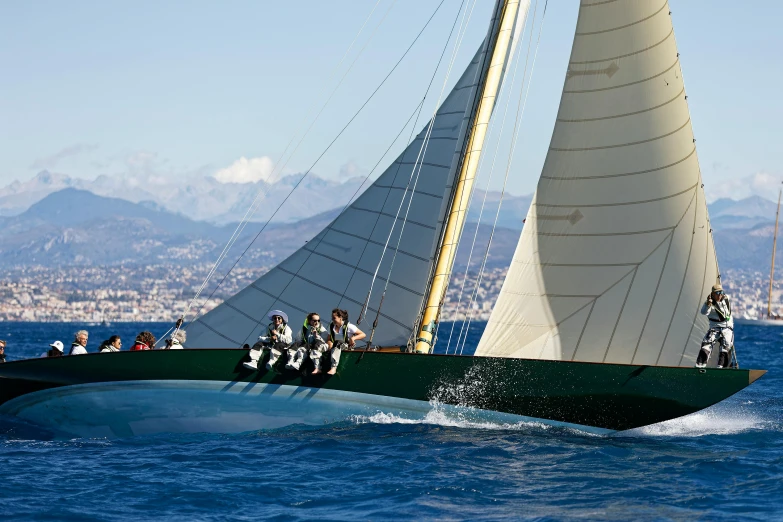 a group of men riding on the back of a green sail boat