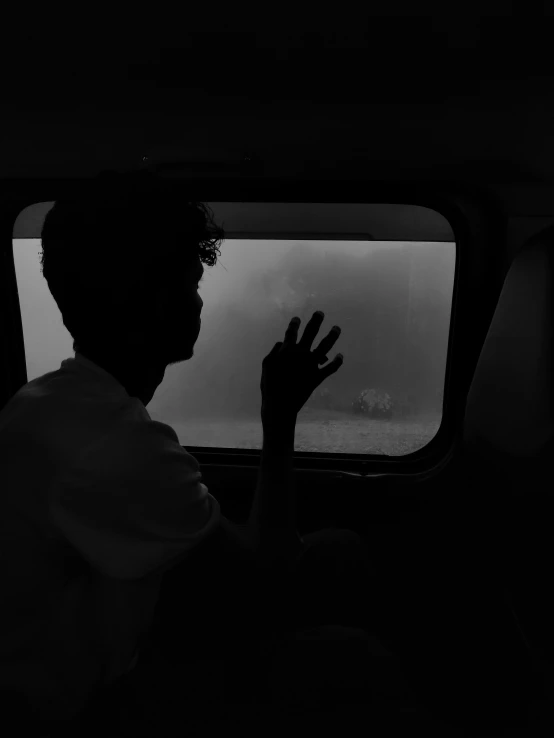 person standing in a vehicle holding their hand out the window