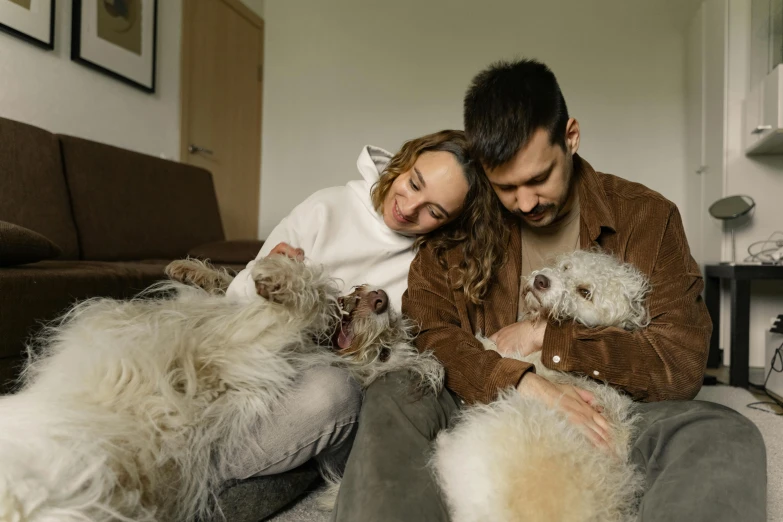 a man and woman are sitting on a couch with three dogs