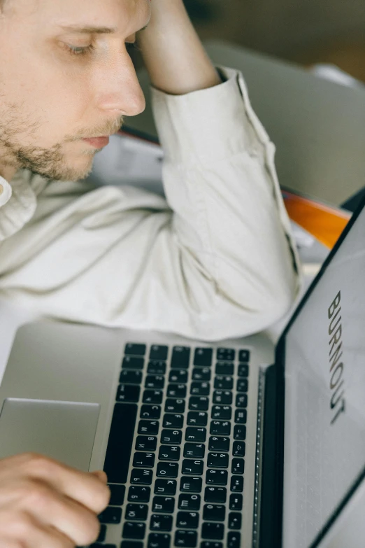 a man holding his head near his eyes while working on his laptop