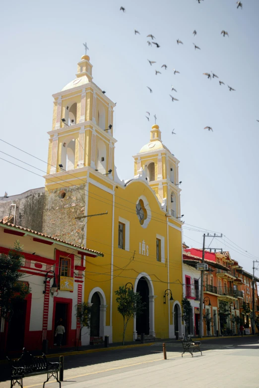 the church has a tower with two crosses on each side and several birds flying around it