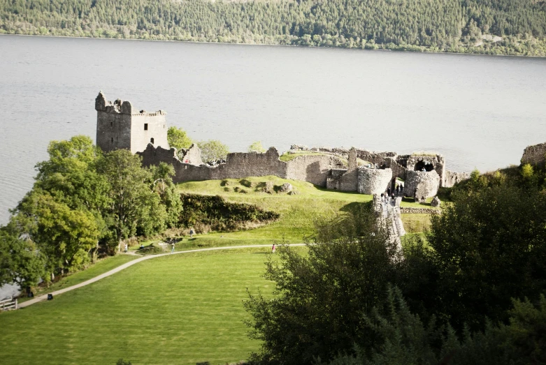 an old castle next to a lake with some cows grazing