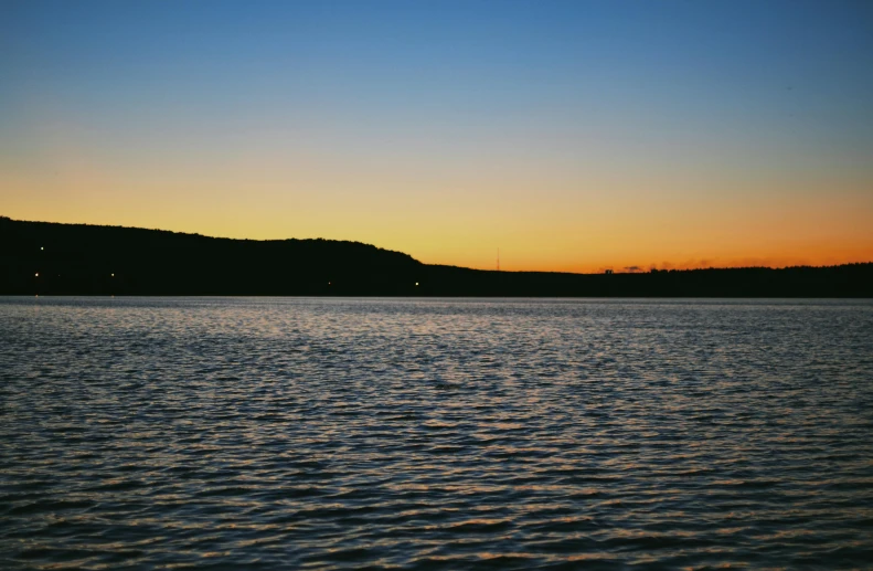 the sun is setting over the ocean with the mountains on the horizon