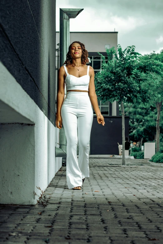 a woman in white standing on the side of a building