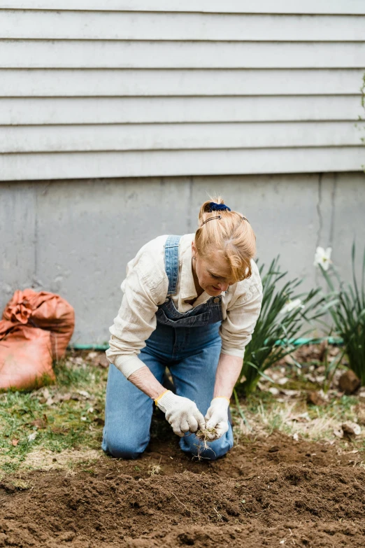 a young woman working in a yard with composthed gloves