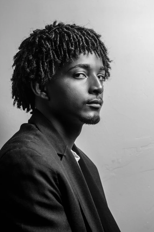 a young man in suit with dreadlocks is looking into the distance