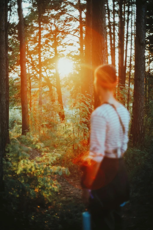 a woman standing in the woods looking out into the distance