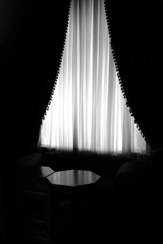 a dark curtained window with curtains hanging in it