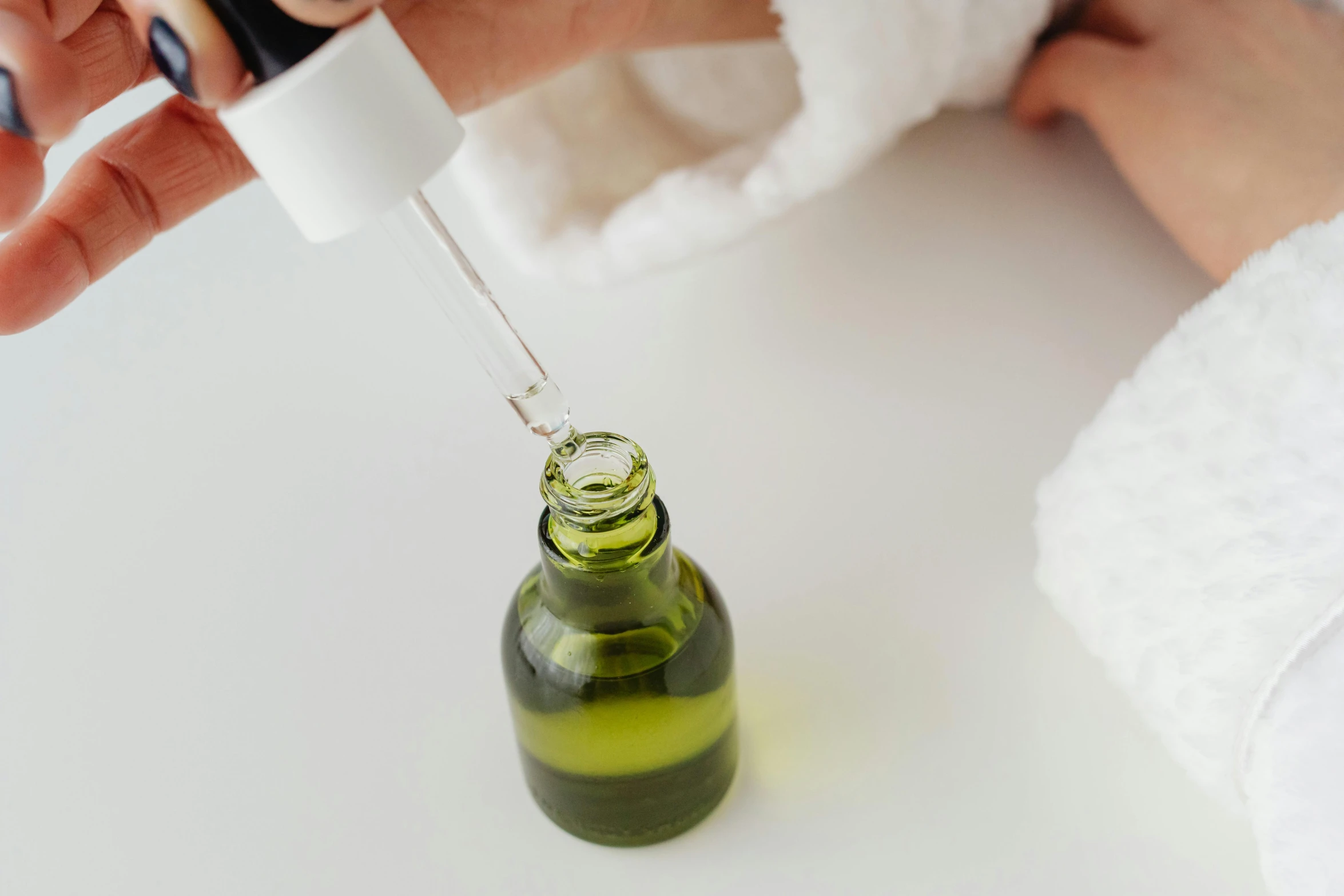 a small green bottle is being filled with lotion