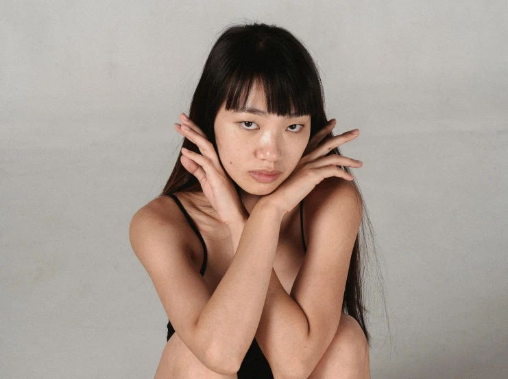 a young woman posing with her hands over her face