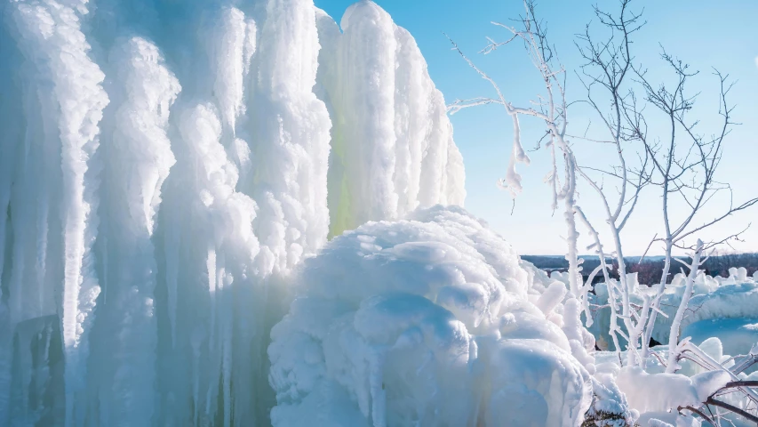 a very long stack of ice sitting next to a tree