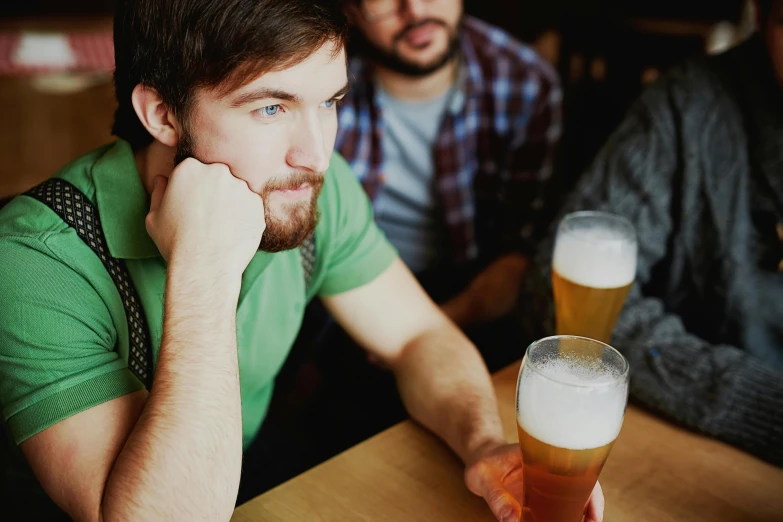 two men at the bar staring toward a beer