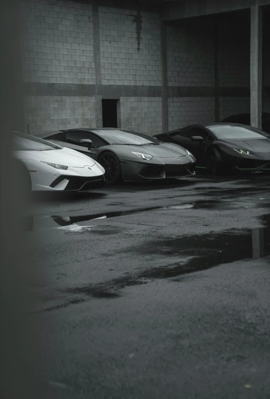 a group of three supercars parked in an indoor parking garage