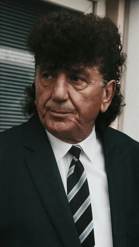 an old man wearing a suit and tie with a black jacket