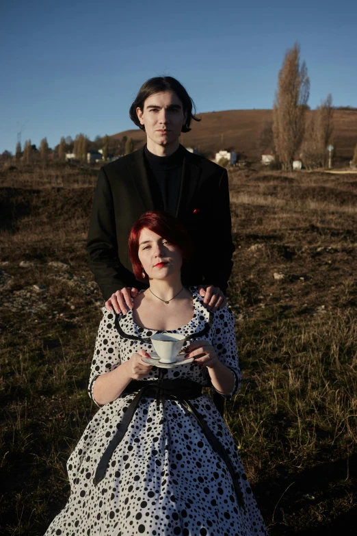 a woman sitting next to a man, in a dress and suit