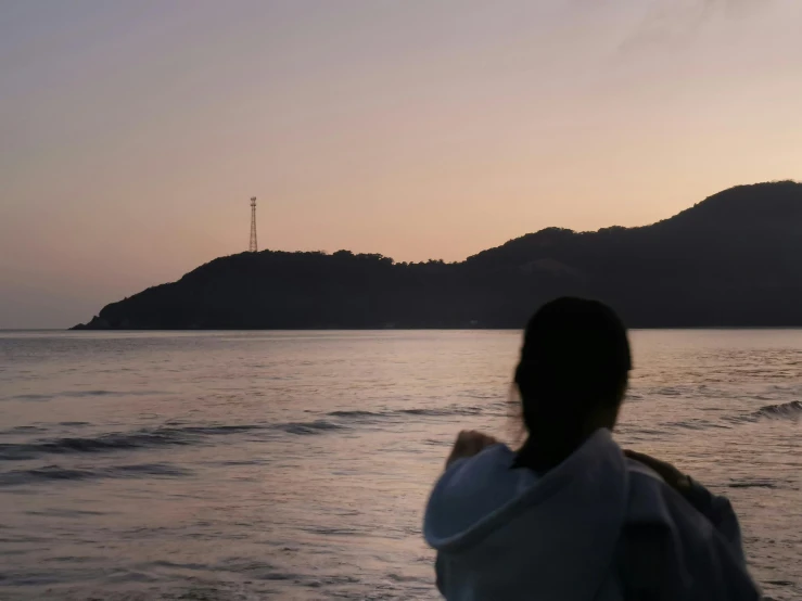 a woman is standing on the water next to a hill