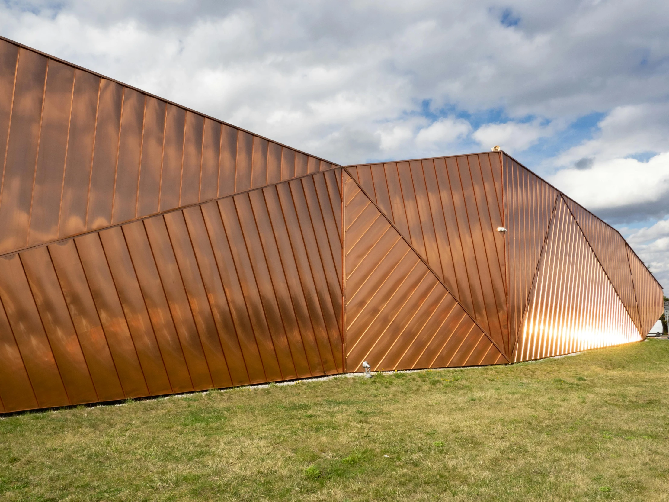 a large gold metal building with green grass and sky