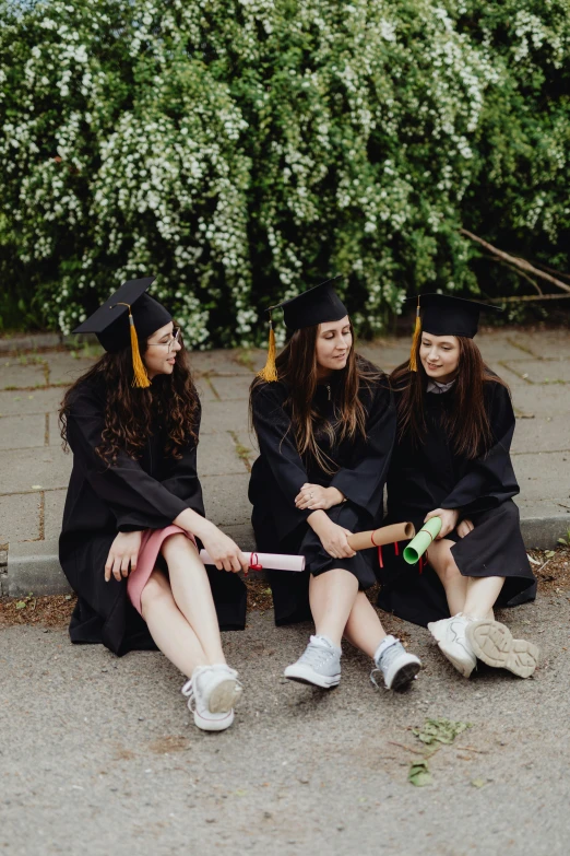 a group of women in graduation gowns sitting on the ground