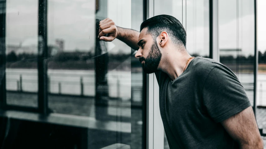 man in black shirt leaning on glass wall