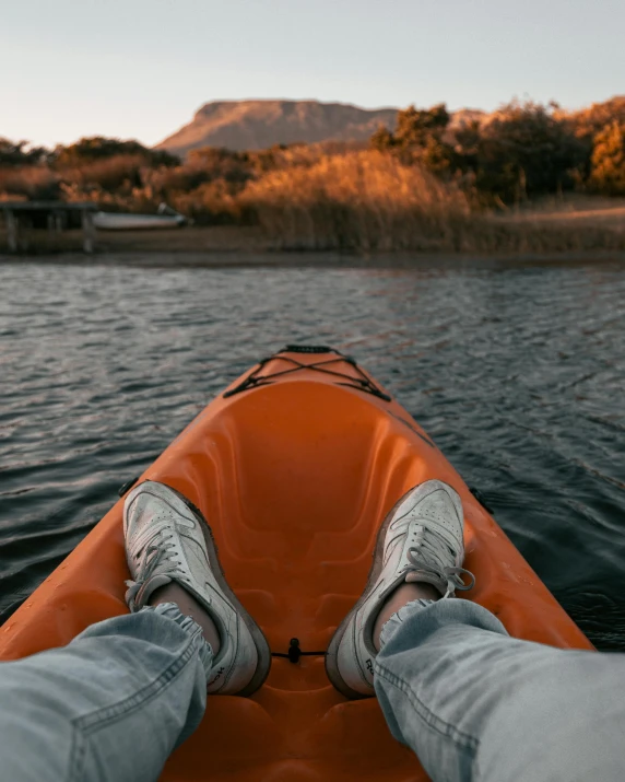 legs of a man sitting on a kayak in a lake