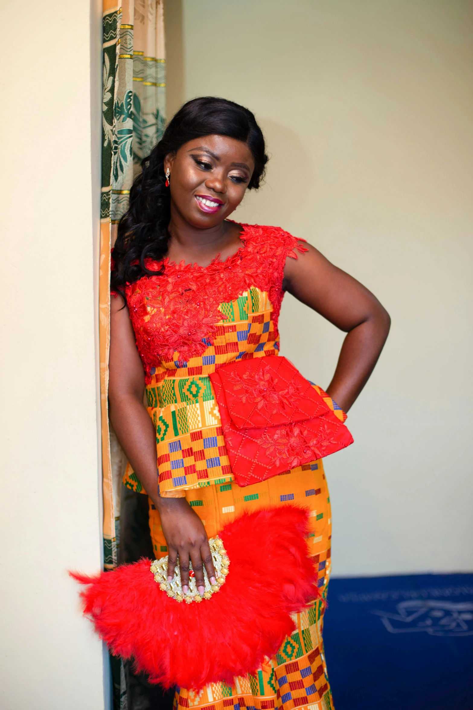 a woman posing next to a door wearing a red dress