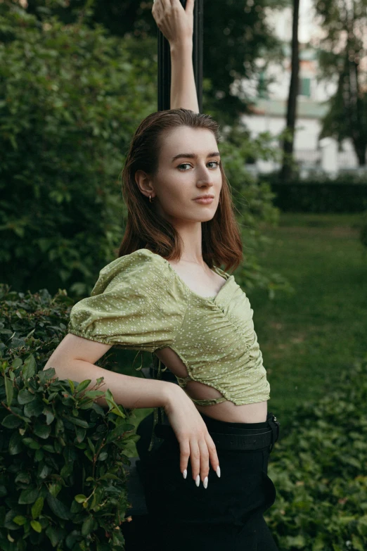 a woman is standing outside in front of bushes