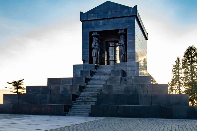 the large clock tower has steps and statues at it's base