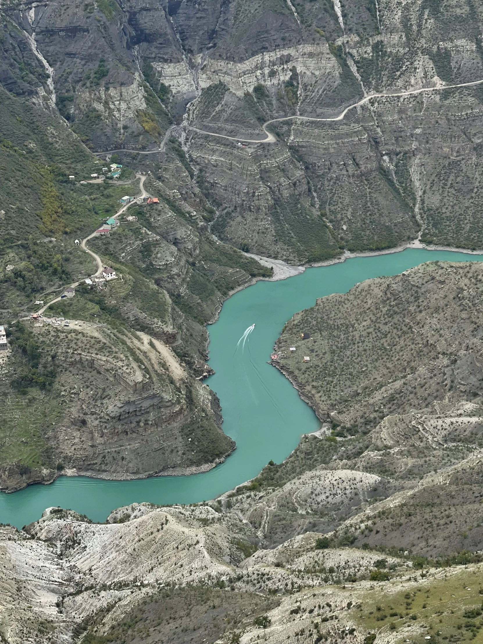 a valley with a stream of water below and houses next to it