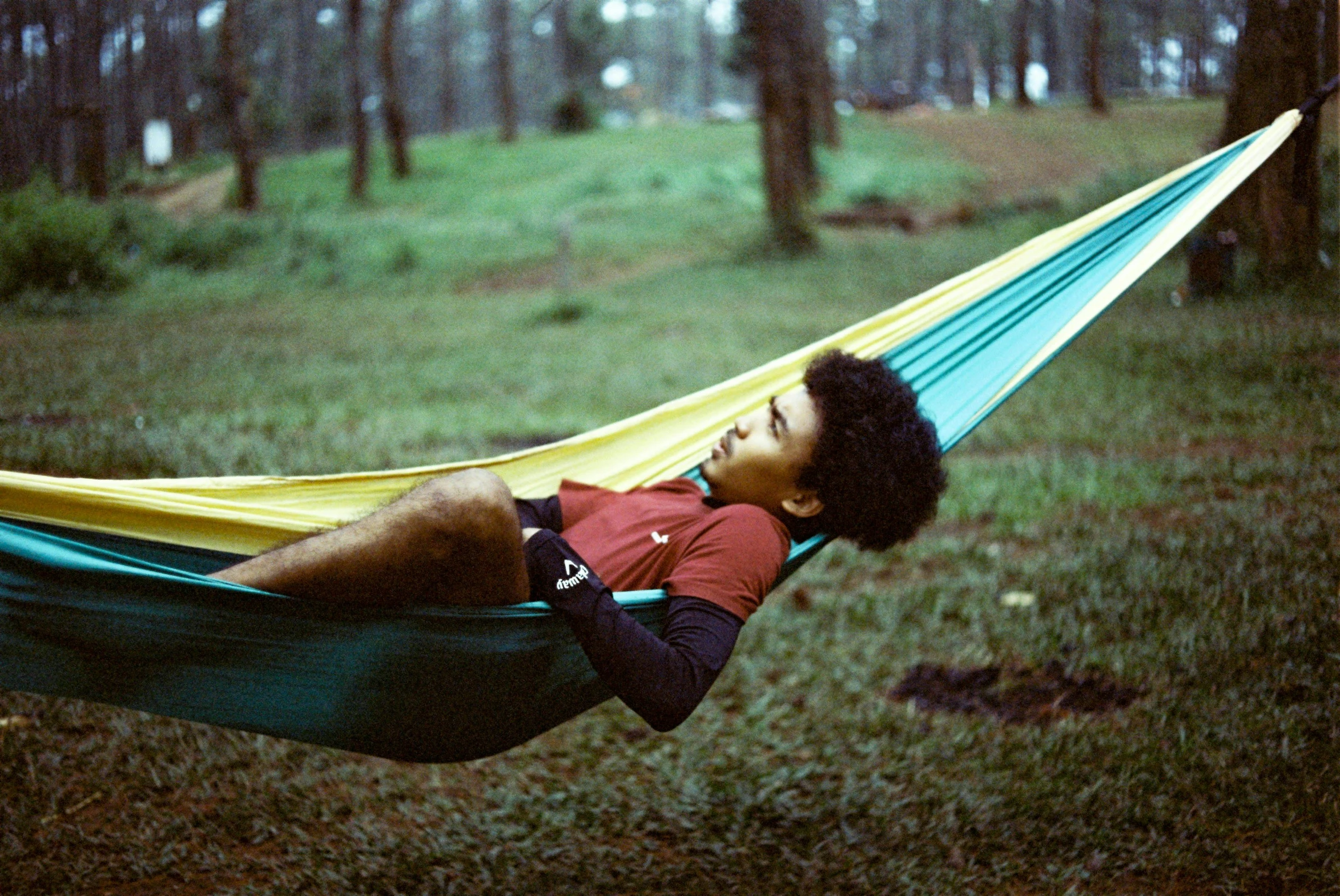 a man is sitting in a hammock with an orange shirt