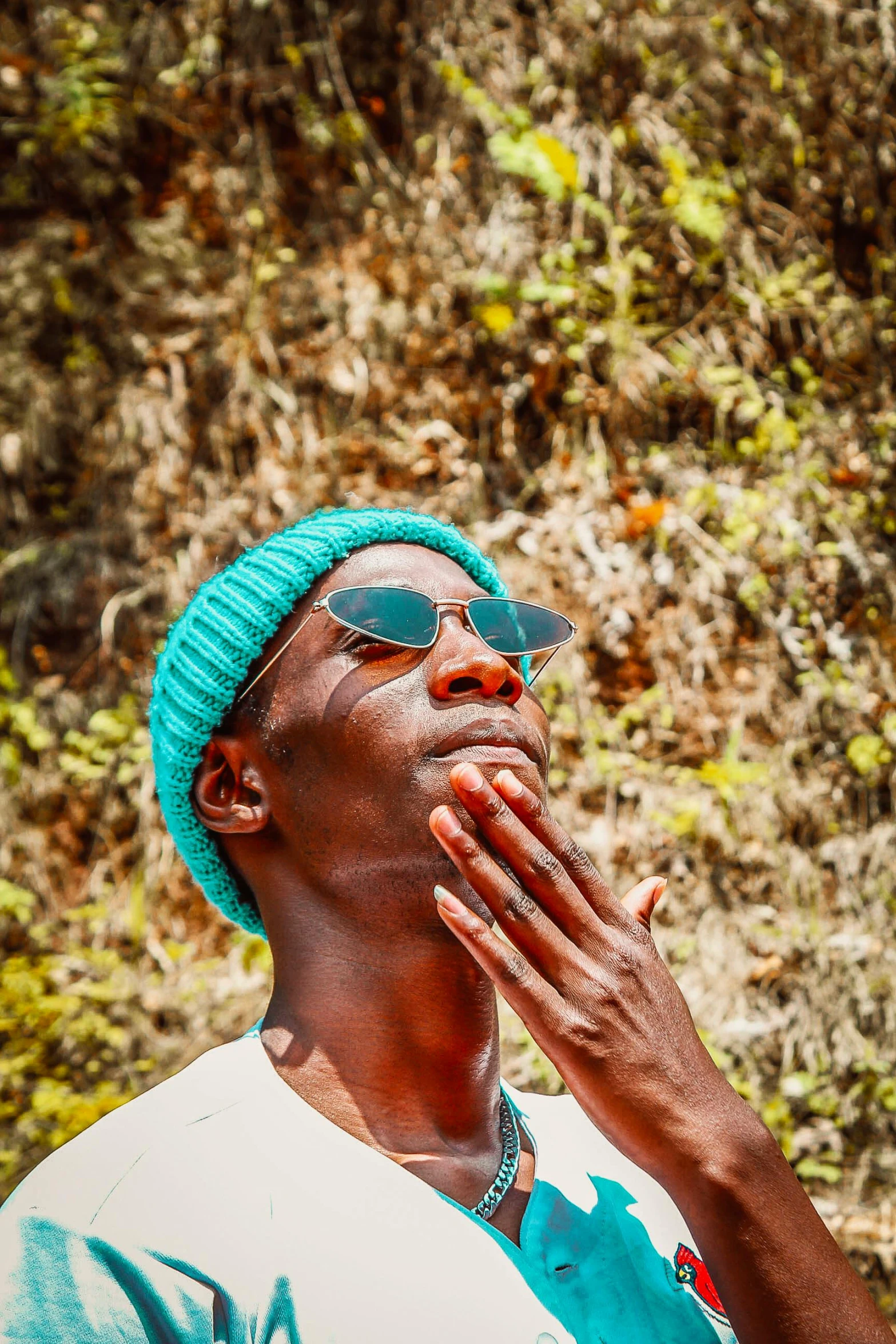 a man in shades and a turban is standing with a hand near his mouth