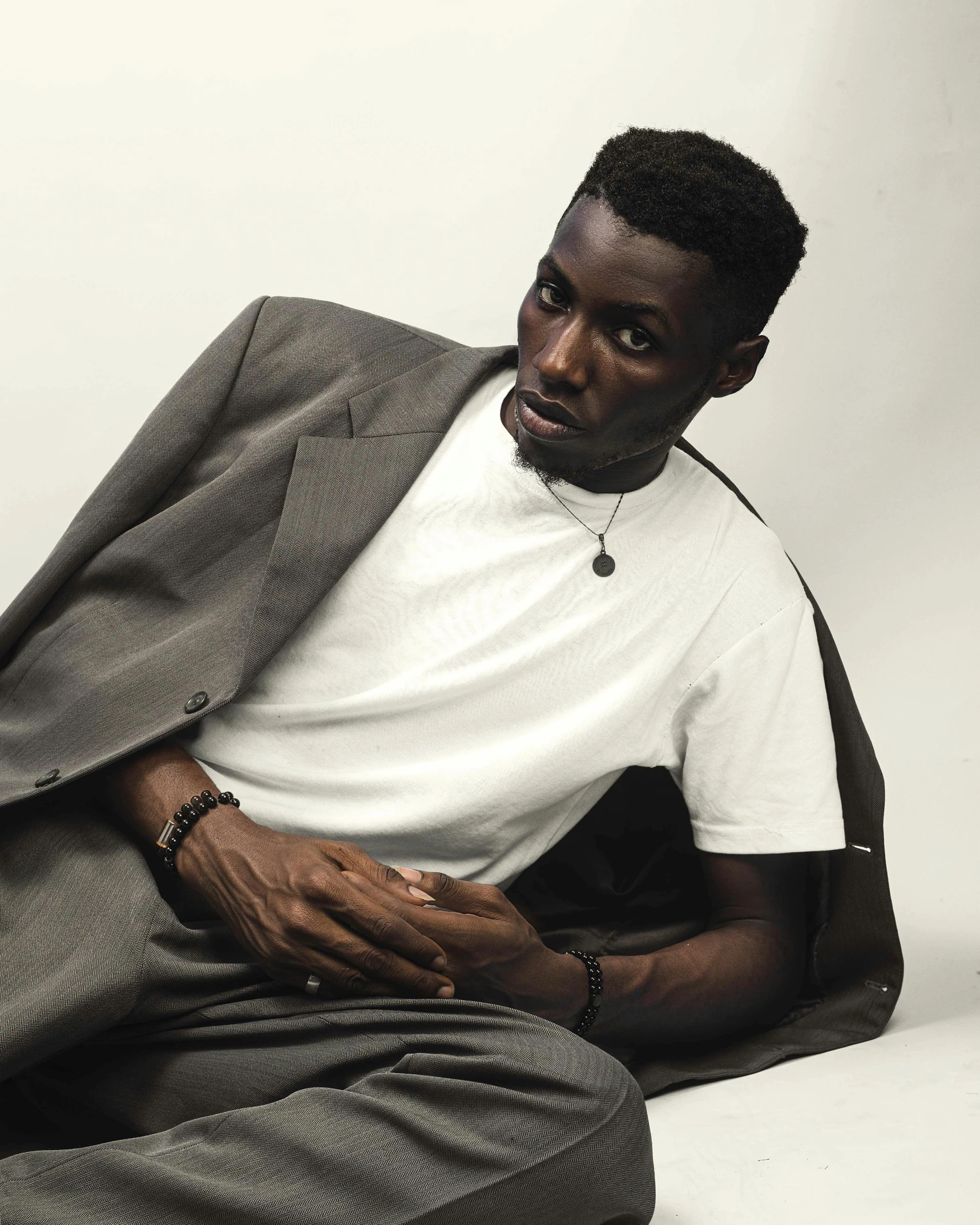 black man wearing white t - shirt and jacket, sitting down