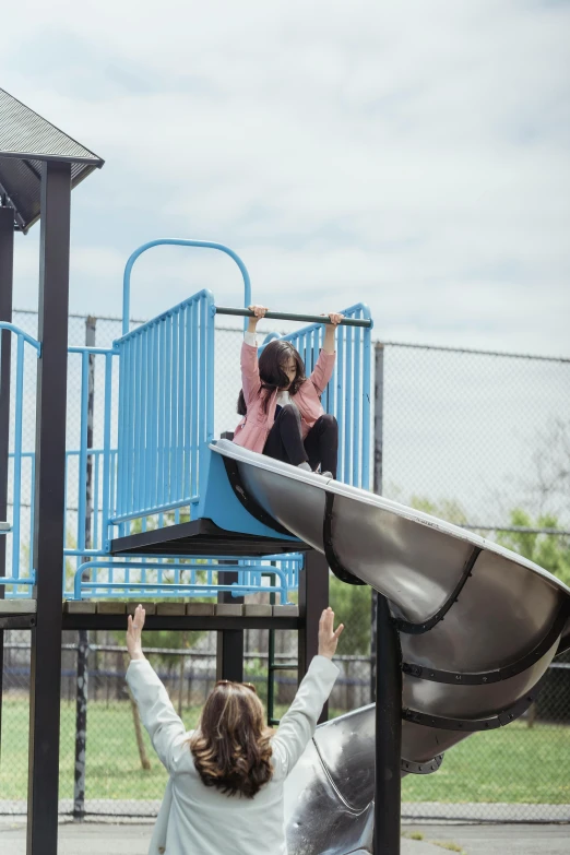 two people are playing in the park on a slide