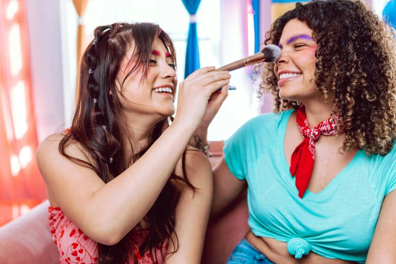 two woman with makeup brushes sitting together