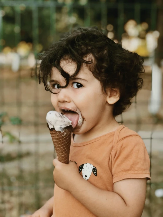 a child with brown shirt eating ice cream