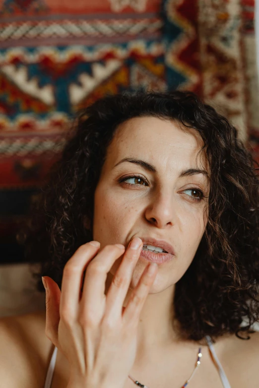 a woman posing and touching her lips in front of a rug