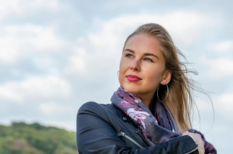 a beautiful woman wearing a black jacket and purple scarf