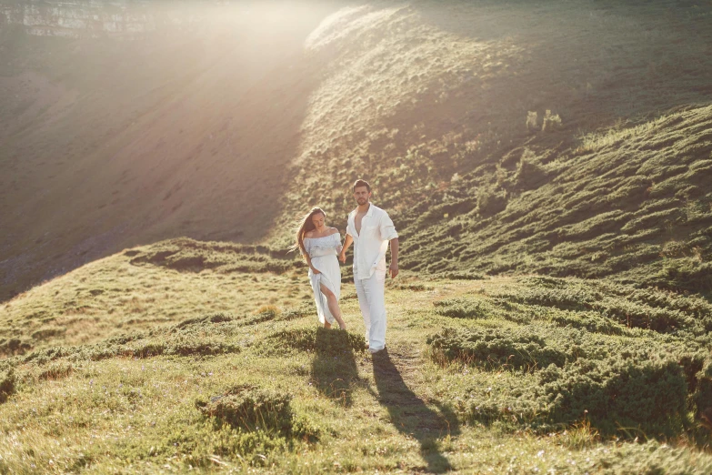 a man and woman in white walking down a hill