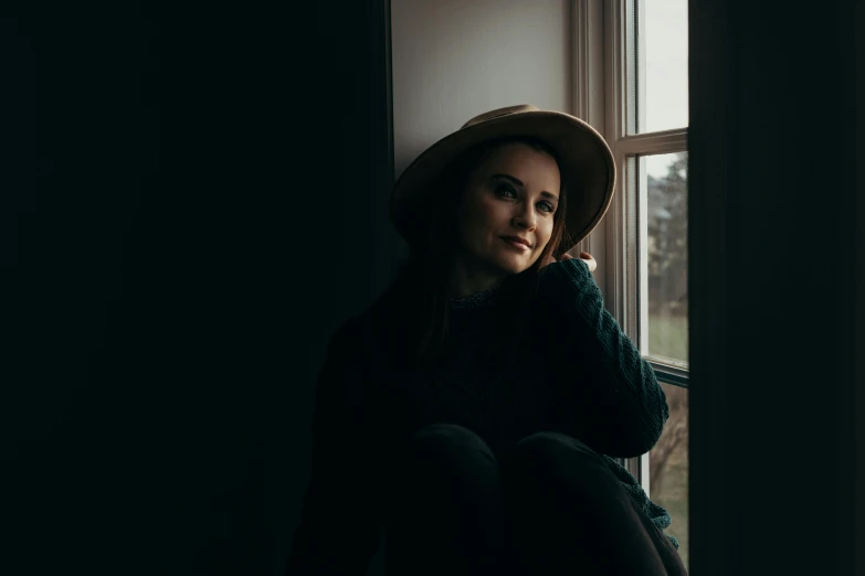 a woman with a hat looking out a window