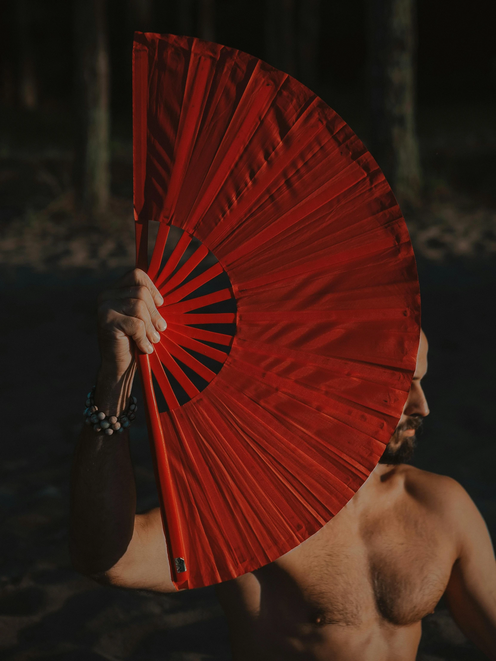 shirtless man holding an oriental style red parasol