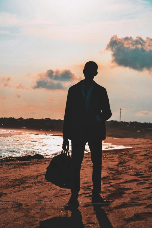 a person holding a suitcase and walking on the beach