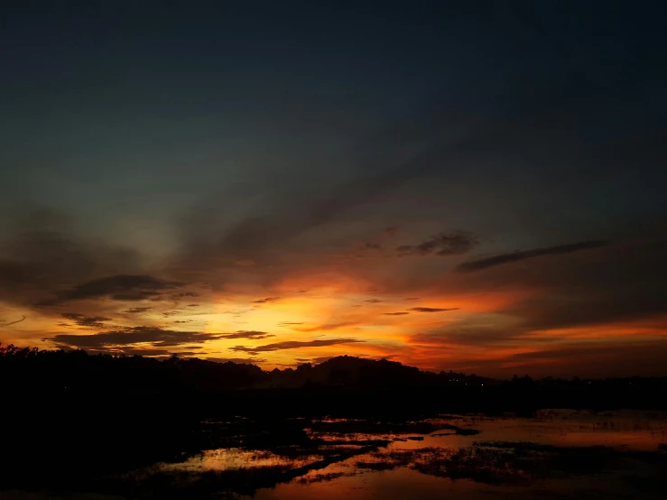 the clouds reflect in the water during sunset