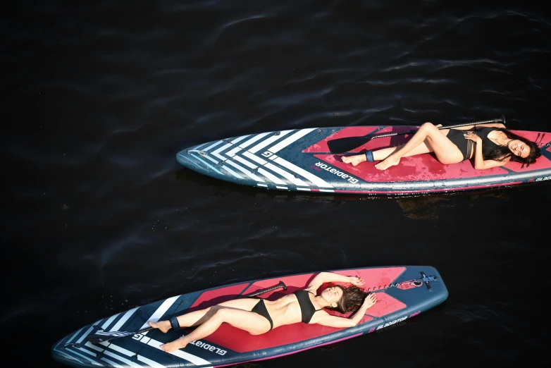 two paddle boarders in the water on a dark background