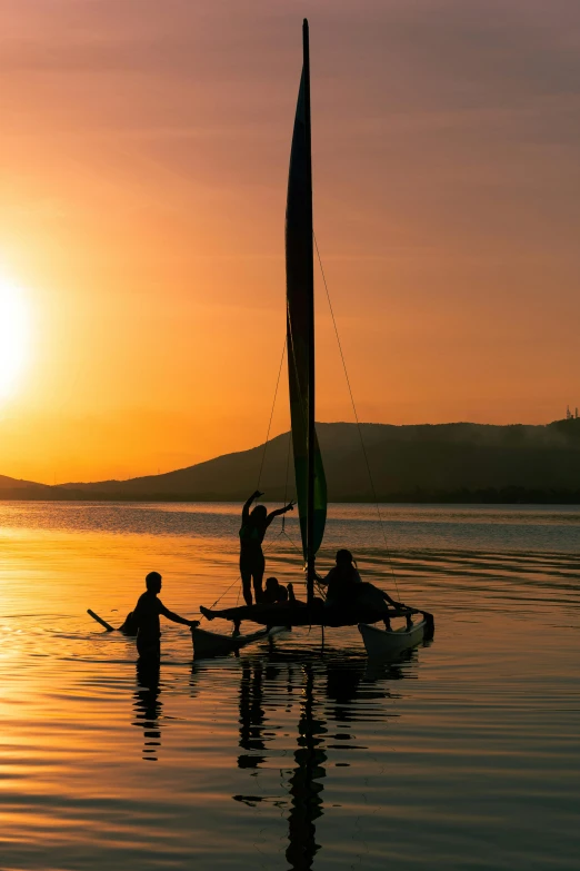 three people rowing their boats at sunset on the ocean