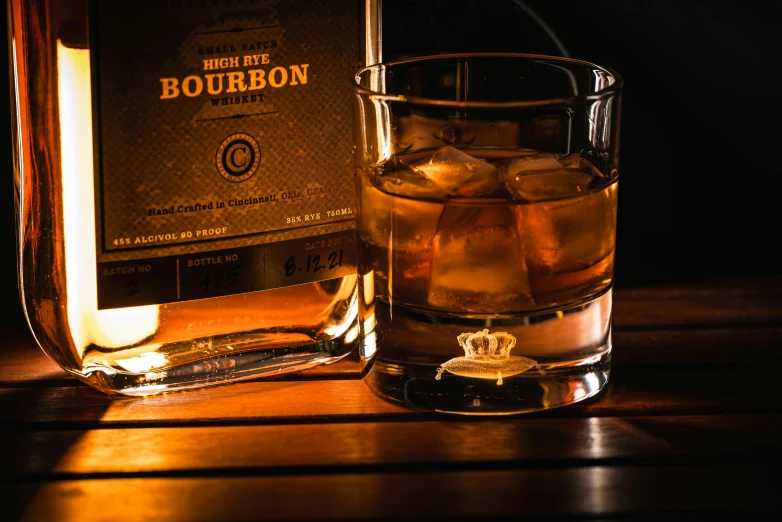 a glass of bourbon and a bottle of bourbon on the table