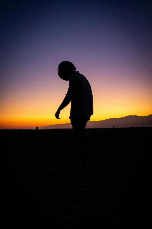 a man standing in the middle of a field as the sun sets