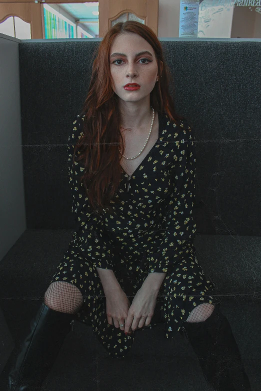 a girl with red hair is sitting on the ground in a cubicle