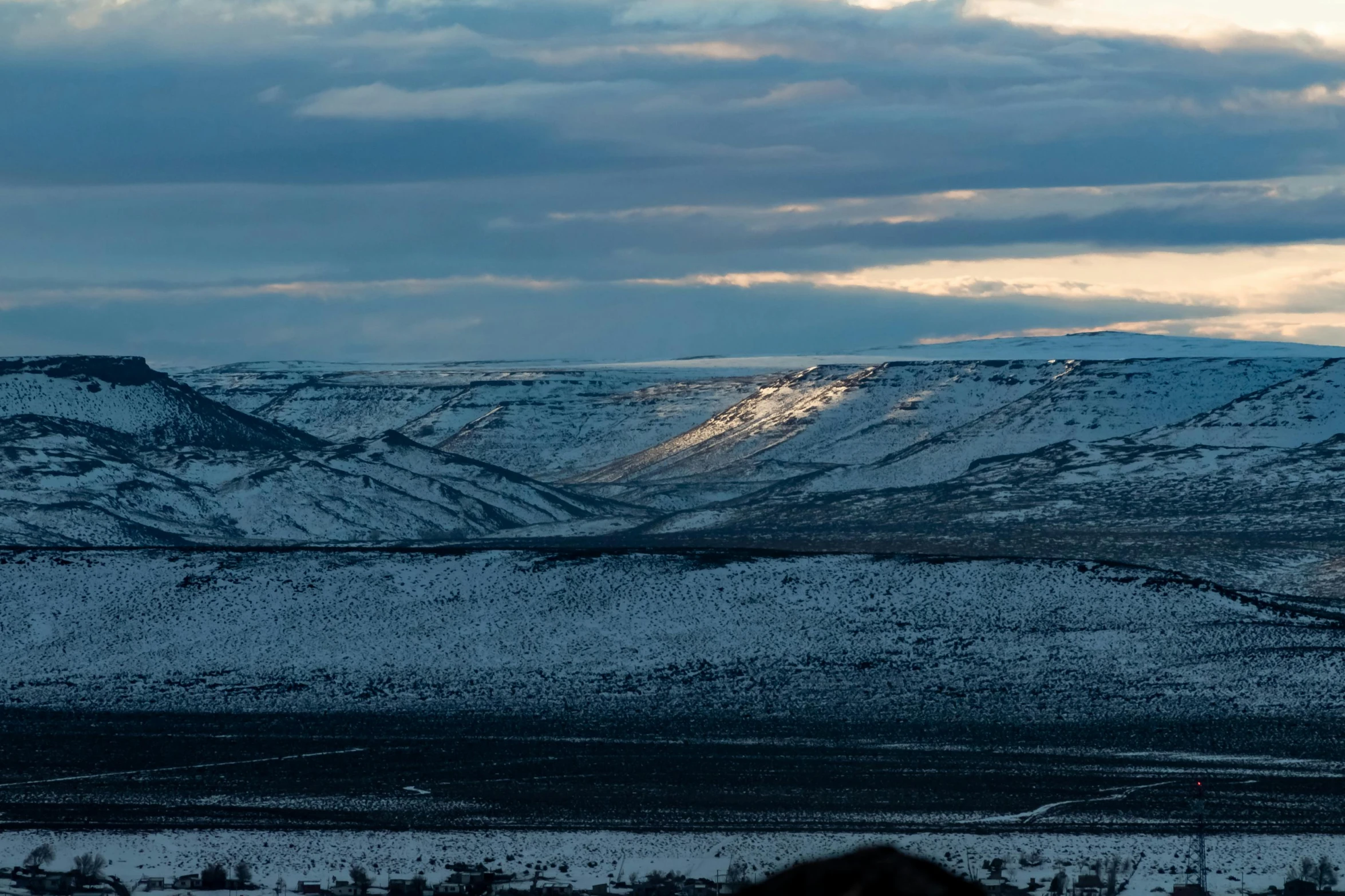 the clouds are covering mountains on a snowy day