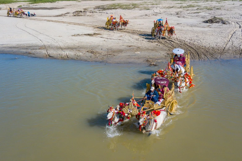 three horses carrying people on the back across water